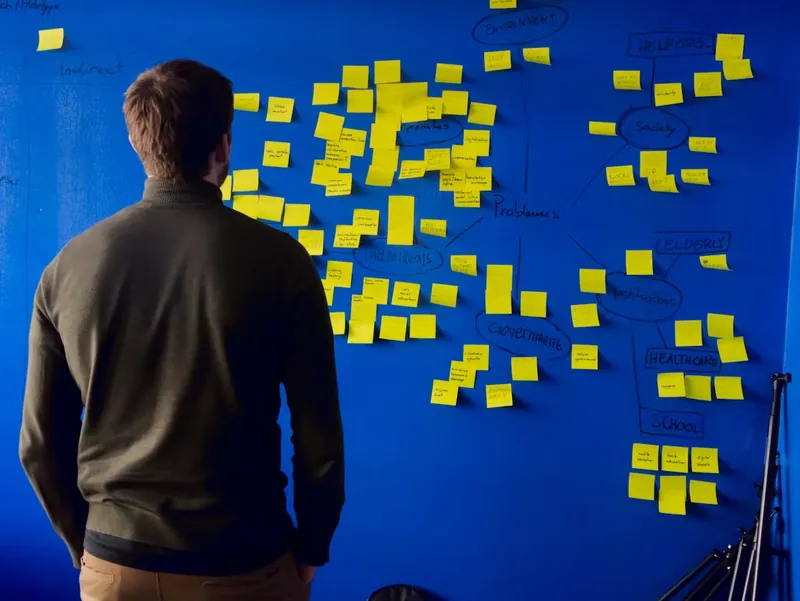 Un fundador organizando ideas en una pared de notas adhesivas
